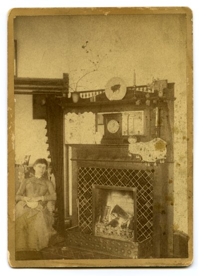 Woman Seated Beside a Lit Fireplace by Unknown